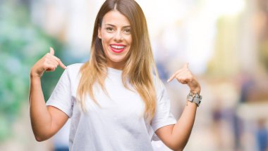 Genç güzel kadın casual beyaz t-shirt üzerine arka yüzünde, gururlu ve mutlu parmak ile işaret kendini gülümseme ile kendine güvenen seyir izole..