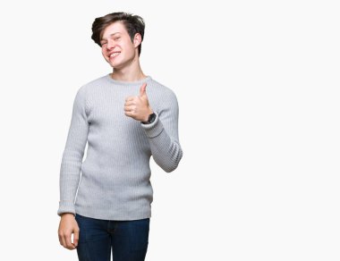 Hareketi el ile mutlu yaşasın yapıyor izole arka plan üzerinde kış kazak giyen genç yakışıklı adam. Başarı gösteren kameraya bakarak ifade onaylama.