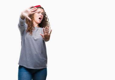 Güzel esmer kıvırcık saçlı Genç kız giyiyor kazak korkuyor ve dehşet korku ifade dur hareketi el ile ile izole arka plan üzerinde şok bağırarak çizgili. Panik kavramı.