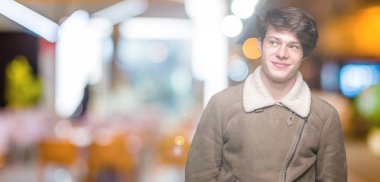 Yakışıklı delikanlı görünümlü yan ve dik dik bakma uzağa düşünce gülümseyen izole arka plan üzerinde kış palto giyiyor.