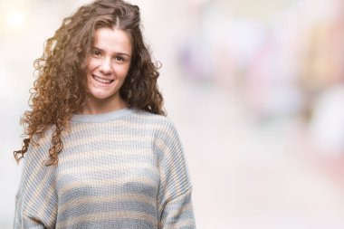 Yüzünde mutlu ve güzel bir gülümseme ile izole arka plan üzerinde kış kazak giyen güzel esmer kıvırcık saçlı Genç kız. Şanslı kişi.