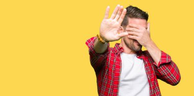 Yakışıklı adam rahat gömlek kapsayan giyen gözleri ile el ve stop jest ile acı ve korku ifadesi. Utandım ve negatif kavramı.