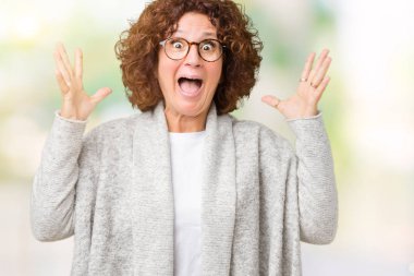 Güzel orta ager üst düzey kadın üzerine ceket ve gözlük takıyor deli kutluyor arka plan izole ve çığlık kaldırdı ve açık gözleri heyecanlı silah ile başarı için hayrete düşürdü. Kazanan kavramı