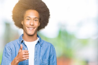 Afrikalı-Amerikalı genç afro saçlı hareketi el ile mutlu yaşasın yapıyor. Başarı gösteren kameraya bakarak ifade onaylama.