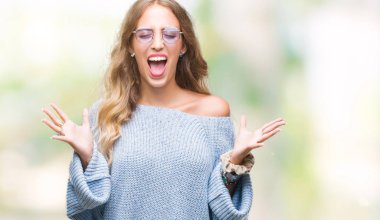 Kızgın ve çığlık kaldırdı ve kapalı gözleri heyecanlı silah ile başarı için deli kutluyor izole arka plan üzerinde güneş gözlüğü takıyor güzel sarışın genç kadın. Kazanan kavramı