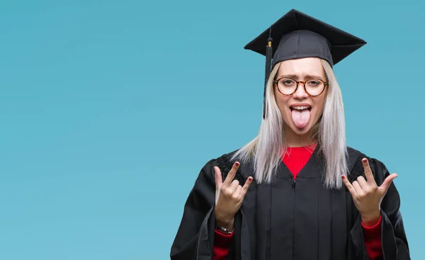 年轻的金发女子穿着毕业制服在孤立的背景下 用疯狂的表情喊着用手做摇滚符号 音乐明星 重的概念 — 图库照片