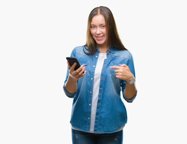 年轻美丽的白人妇女短信发送消息使用智能手机在孤立的背景与惊讶的脸指向自己的手指 — 图库照片