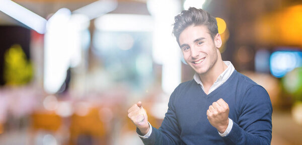 Young handsome business man over isolated background very happy and excited doing winner gesture with arms raised, smiling and screaming for success. Celebration concept.