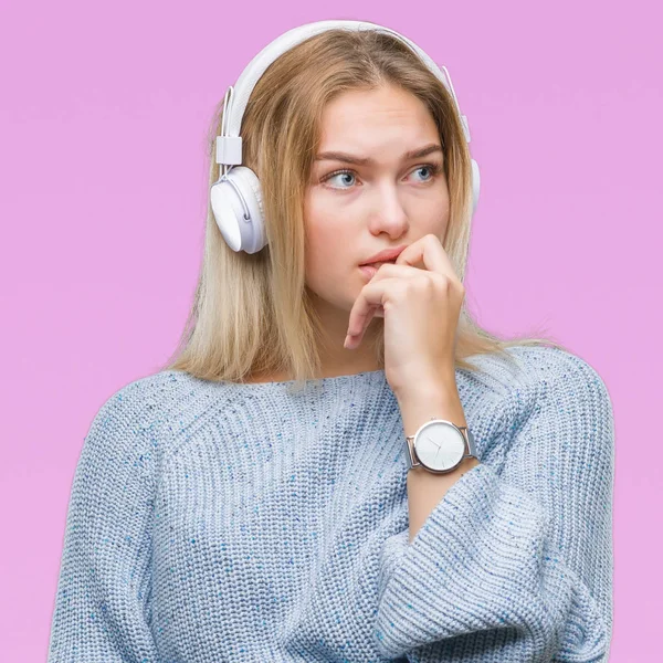 Young caucasian woman listening to music wearing headphones over isolated background looking stressed and nervous with hands on mouth biting nails. Anxiety problem.