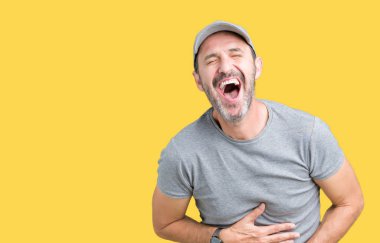 Yakışıklı orta yaş ağarmış kıdemli giyiyor spor kap üzerinde izole adam arka plan gülen ve komik deli şaka çünkü yüksek sesle zor gülüyor. Mutlu ifade.