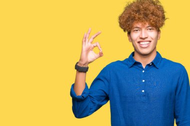 Afro saç gülümseyen genç yakışıklı zarif adam el ve parmaklar ok işaretiyle yapıyor olumlu. Başarılı ifade.