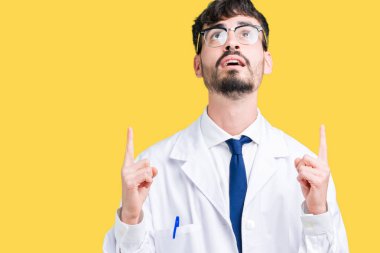 İzole arka plan üzerinde beyaz önlük giyen hayret ve yukarıya bakıp parmakları ile işaret şaşırttı ve silah kaldırdı genç profesyonel bilim adamı.