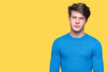 Genç yakışıklı adam yüzünde ciddi bir ifade ile izole arka plan üzerinde mavi kazak giyiyor. Basit ve doğal kameraya bakıyor.