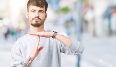 Yakışıklı delikanlı kazak izole arka plan yapıyor zaman aşımı jest elle, sinirli üzerinde ve ciddi bir yüz