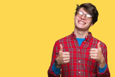 Yakışıklı delikanlı izole arka plan başarı işareti el ile pozitif jest yapıyor üzerinde gözlük takan başparmak gülümseyen ve mutlu. Neşeli bir ifadeyle, kazanan jest kameraya bakıyor.