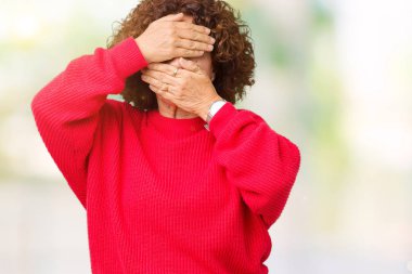 Güzel orta ager üst düzey kadın kırmızı kış kazak izole arka plan kaplaması gözler ve ağız el ile üzerinden şaşırttı ve şok. Duygu gizleme