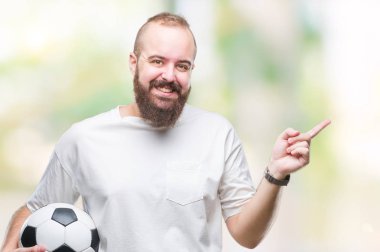 Futbol futbol topu izole arka plan üzerinde çok mutlu el ve parmak ile tarafına işaret tutan genç beyaz hipster adam