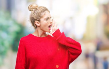 Bağırarak ve ağzı üzerinde el ile yan için çığlık izole arka plan üzerinde kırmızı kazak ve gözlük giyen genç güzel sarışın kadın. İletişim kavramı.