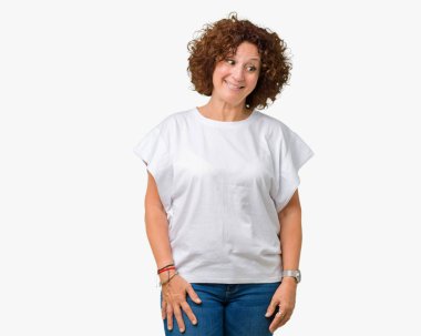 Görünümlü yan ve dik dik bakma uzağa düşünce gülümseyen izole arka plan üzerinde beyaz t-shirt giyen güzel orta ager üst düzey kadın.