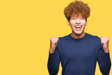 Afro saç kutlama ile yakışıklı delikanlı şaşırttı ve başarı için kaldırdı kollarını açarak hayret ve gözleri açık. Kazanan kavramı.