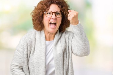 Güzel orta ager üst düzey kadın üzerine ceket ve gözlük takıyor arka plan kızgın izole ve kızgın yetiştirme hayal kırıklığı ve öfke ile bağırarak süre öfkeli yumruk. Öfke ve agresif kavramı.