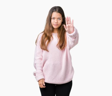 Stop yapıyor izole arka plan üzerinde pembe kış kazak giyen genç güzel esmer kadın elin avuç ile şarkı. Negatif ve ciddi bir jest yüz ifadesiyle uyarı.