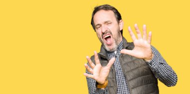 Şokta bağırarak kış yeleği korkuyor ve dehşet korku ifade dur hareketi el ile ile orta yaş yakışıklı adam. Panik kavramı.