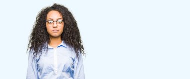 Kıvırcık saçlı gevşek ciddi ifade ile yüzünde gözlüklü genç güzel iş kız. Basit ve doğal kameraya bakıyor.