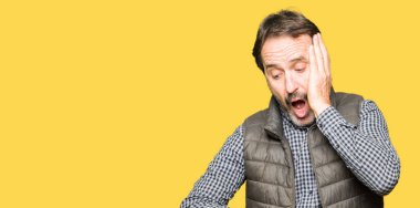 Orta yaş yakışıklı adam giyen kış yelek Looking seyretmek zaman endişeli, geç korkuyor