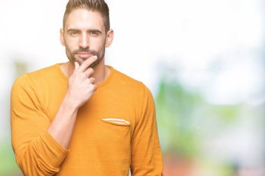 Yakışıklı delikanlı emin çapraz kollar ve çeneme kaldırdı el ile gülümseme ile kameraya bakarak izole arka plan üzerinde. Pozitif düşünce.