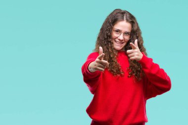 Güzel esmer kıvırcık saçlı Genç kız için fotoğraf makinesi ile mutlu ve komik yüz parmakları işaret izole arka plan üzerinde gözlük ve kış kazak giyiyor. İyi enerji ve vibes.