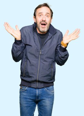 Bir ceket clueless ve şaşkın ifadeyle kollar ve eller kaldırdı giyen orta yaş yakışıklı adam. Şüphe kavramı.