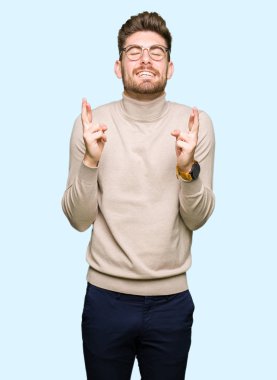 Umut ve gözleri kapalı geçiş parmaklarıyla gülümseyen gözlüklü genç yakışıklı iş adamı. Şans ve batıl kavramı.