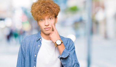 Afro saçlı kot giyen genç yakışıklı adam ceket işaret jest göz izlemek için şüpheli ifade