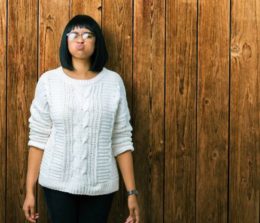 Komik surat ile yanakları şişirme izole arka plan üzerinde gözlük güzel genç Afro-Amerikan kadın. Ağız ile hava, deli ifade şişirilmiş.