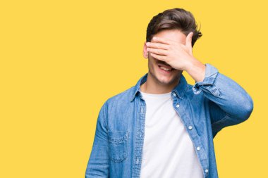 Genç yakışıklı adam gülümsüyor ve gözleri için sürpriz kapsayan yüz el ile gülüyor izole arka plan üzerinde güneş gözlüğü takıyor. Kör kavramı.