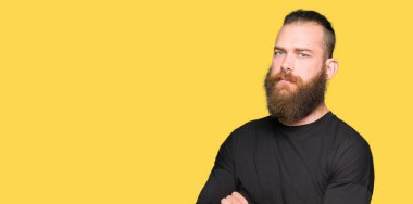 Genç sarışın adam rahat t-shirt şüpheci ve sinir, onaylamayan ifade yüz çapraz kollu giyiyor. Negatif kişi.