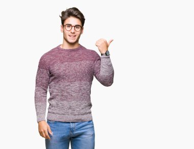 Seyir ve başparmak yanında yukarıyı mutlu yüz ile gülümseyen izole arka plan üzerinde gözlük takan genç yakışıklı adam.