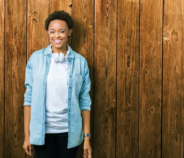 Yüzünde mutlu ve güzel bir gülümseme ile izole arka plan üzerinde kulaklık giyen genç Afro-Amerikan kadın. Şanslı kişi.