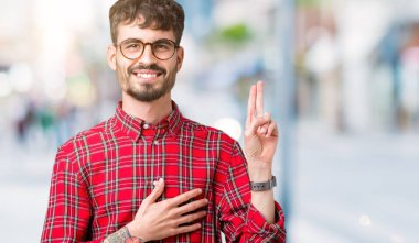 Genç yakışıklı adam gözlük izole üzerinden Swearing göğüs ve bir sadakat sözü yemin yapma parmaklar, el ile arka plan