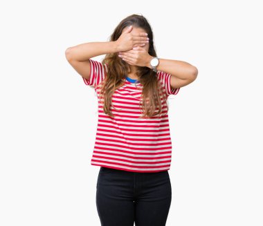 Giyen genç güzel esmer kadın çizgili tişört izole arka plan üzerinde gözler ve ağız el ile kapsayan şaşırttı ve şok. Duygu gizleme