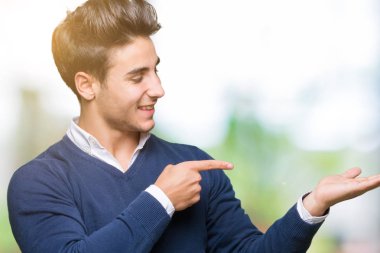 Genç yakışıklı iş adamı üzerinden hayran ve el ile sunulması ve parmak ile işaret ederken kameraya gülümseyen izole arka plan.