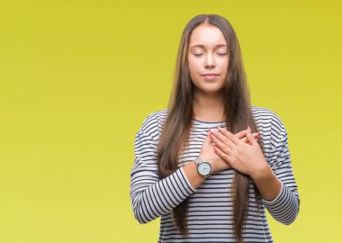 Eller genç güzel beyaz kadın ile gülümseyen izole arka plan üzerinde kapalı gözler ve yüzünde minnettar jest ile göğüs üzerinde. Sağlık kavramı.