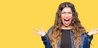 Gözlük ve kot giyen genç güzel kadın ceket kutluyor deli ve çığlık kaldırdı ve açık gözleri hayret silah ile başarı için heyecanlı. Kazanan kavramı