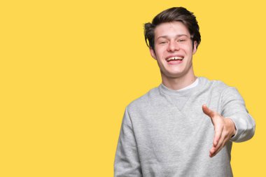 Tebrik ve davet edici dostu sunan karşılıklı gülümseyen izole arka plan üzerinde sweatshirt giyen genç yakışıklı sportif adam. Başarılı iş.