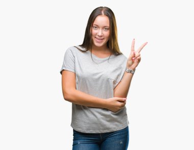 Mutlu yüz zafer işareti yaparken kameraya göz kırpıyor ile gülümseyen izole arka plan üzerinde genç Kafkas güzel kadın. İki numaralı.