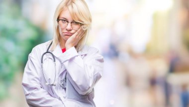 Düşünme izole arka plan bakmaktan Tıbbi üniforma giyen genç güzel sarışın doktor kadın yorgun ve sıkılmış çapraz silah depresyon sorunları ile.