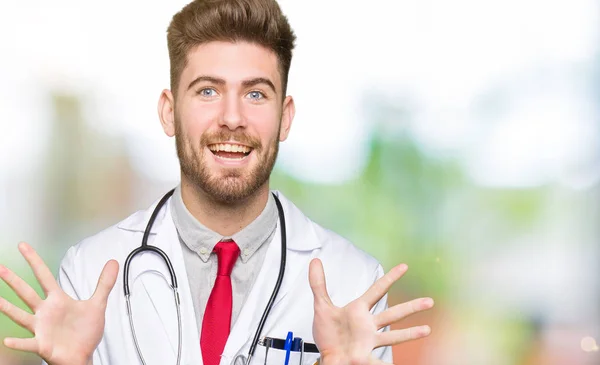 Homem Médico Bonito Jovem Vestindo Casaco Médico Celebrando Louco Espantado — Fotografia de Stock