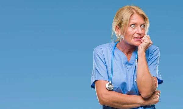 中年ブロンドの看護師の外科医不安や両手の爪を噛んで口の中で緊張を探して孤立の背景に女性医師 不安の問題 — ストック写真