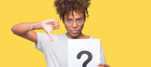 Young african american woman holding paper with question mark over isolated background with angry face, negative sign showing dislike with thumbs down, rejection concept